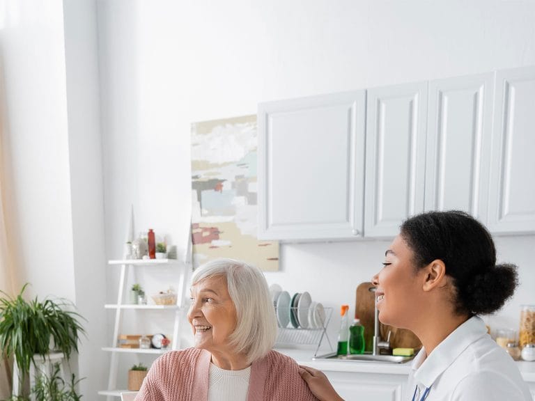 A care worker chatting with an older woman over a meal at home